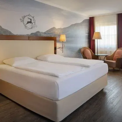 The Fuschl Comfort XL room in the Arabella Jagdhof Resort am Fuschlsee showing a bed and two chairs