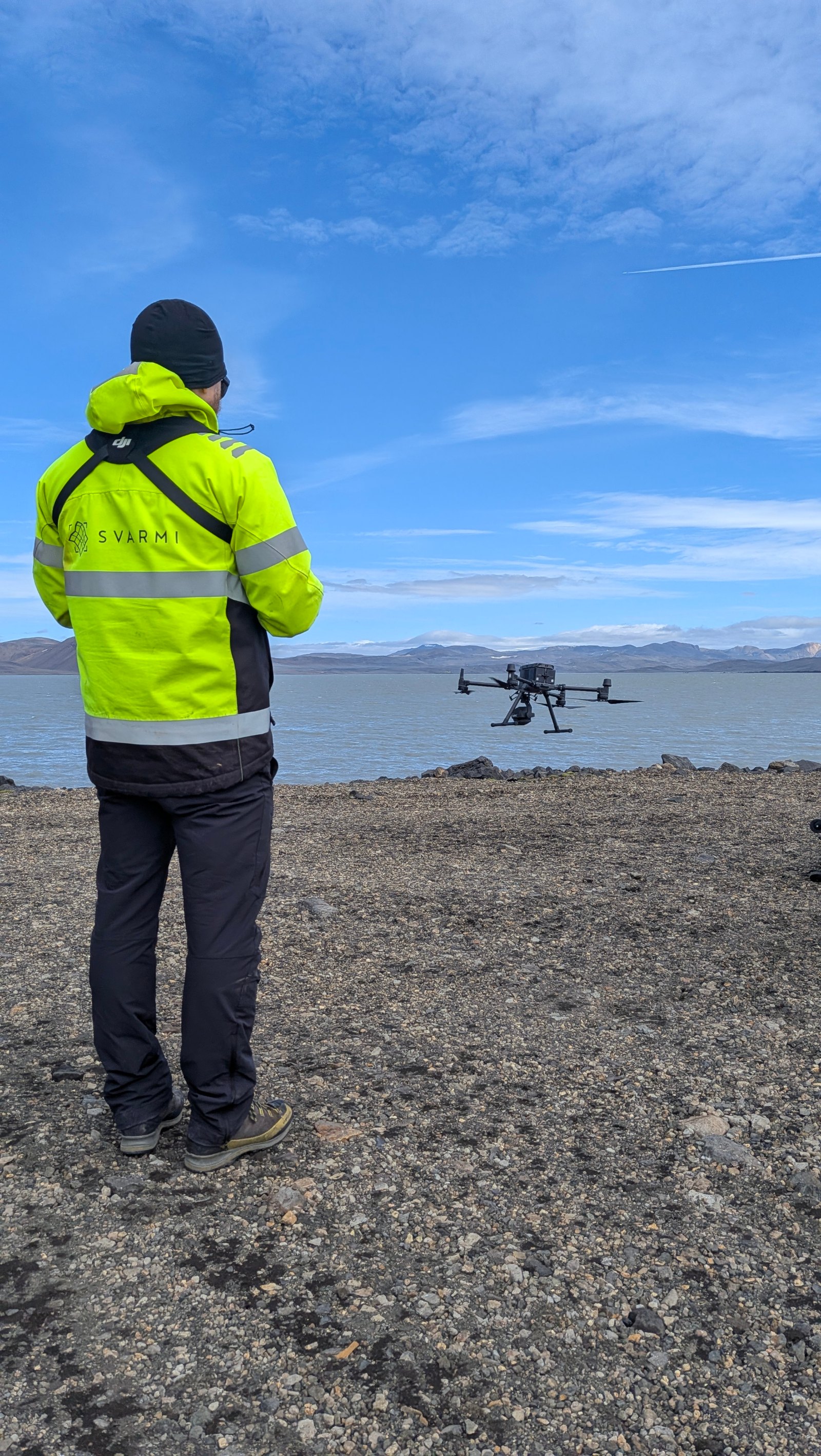 Svarmi remote pilot in high-visibility jacket flying a survey drone over a lake in the Icelandic highlands | Svarmi