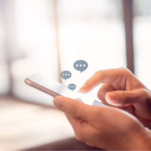 Person using a smartphone with digital chat bubbles appearing above the screen.