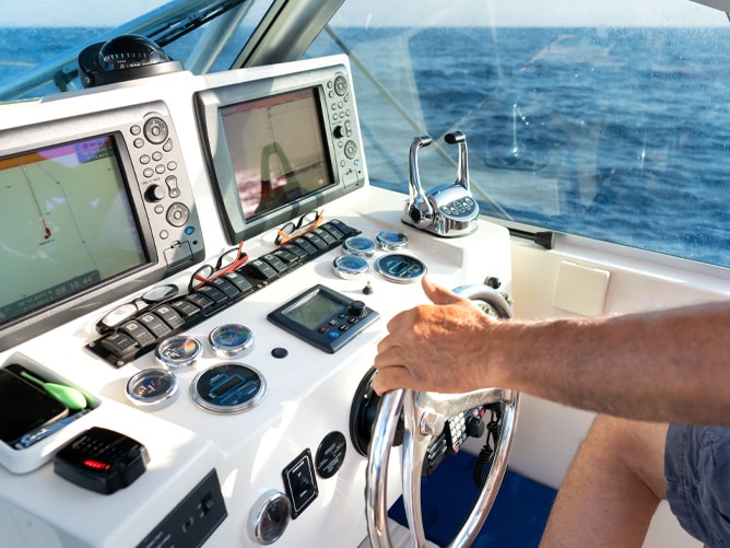 Man steering boat, dashboard and electronics front and centre.