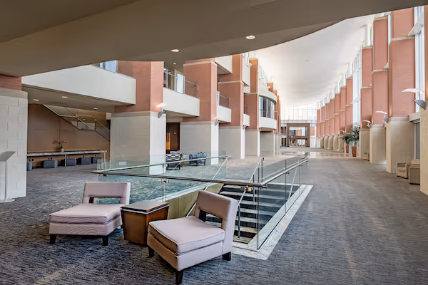 Modern interior with pink chairs, glass railings, and architectural geometric design
