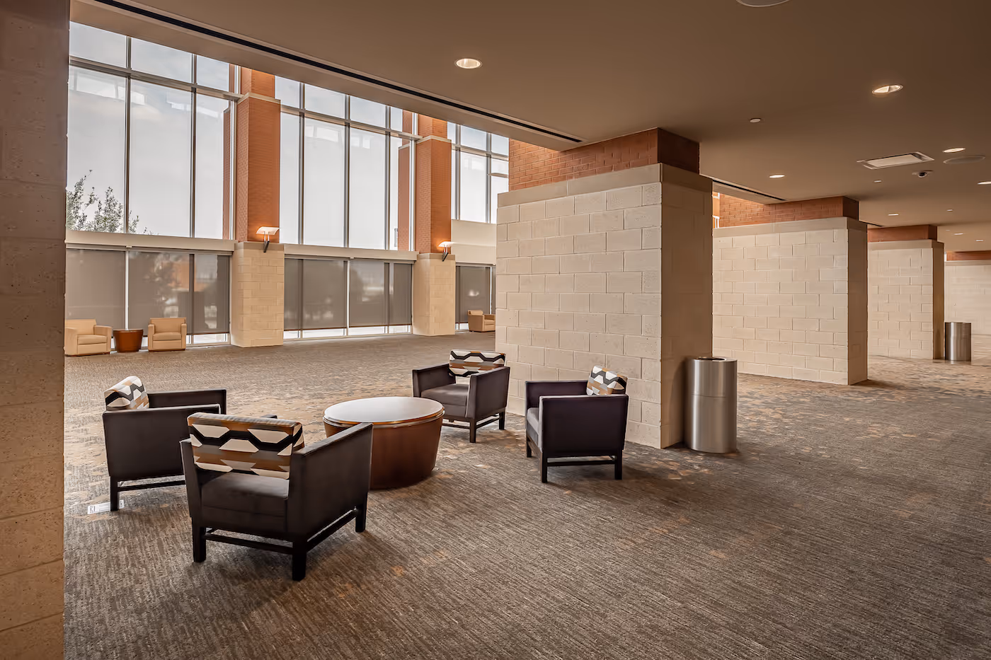 Modern lobby with dark chairs, round table, and large windows