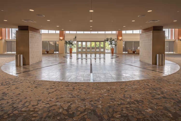 Spacious modern lobby with tiled floor, recessed lighting, and potted plants
