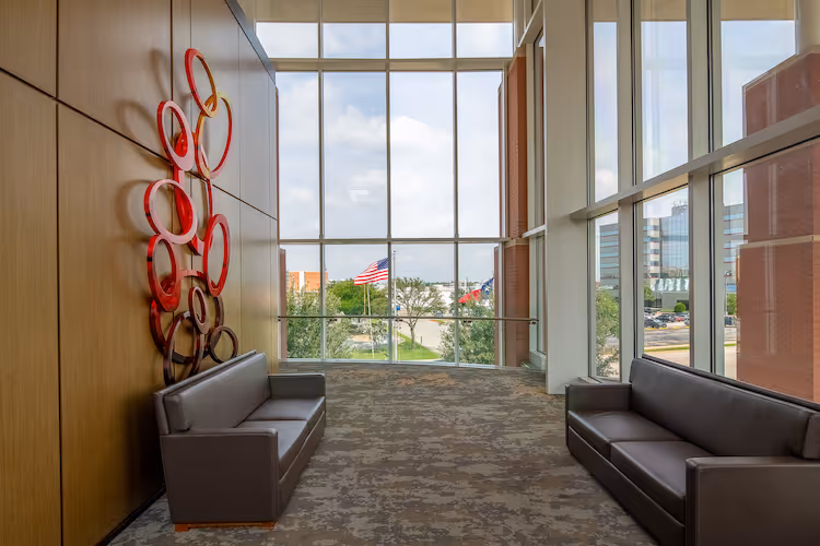 Modern waiting area with red art sculpture, large windows, and American flag