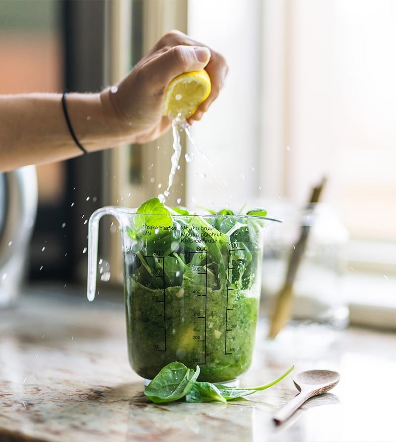 Squeezing lemon juice into a pitcher of greens