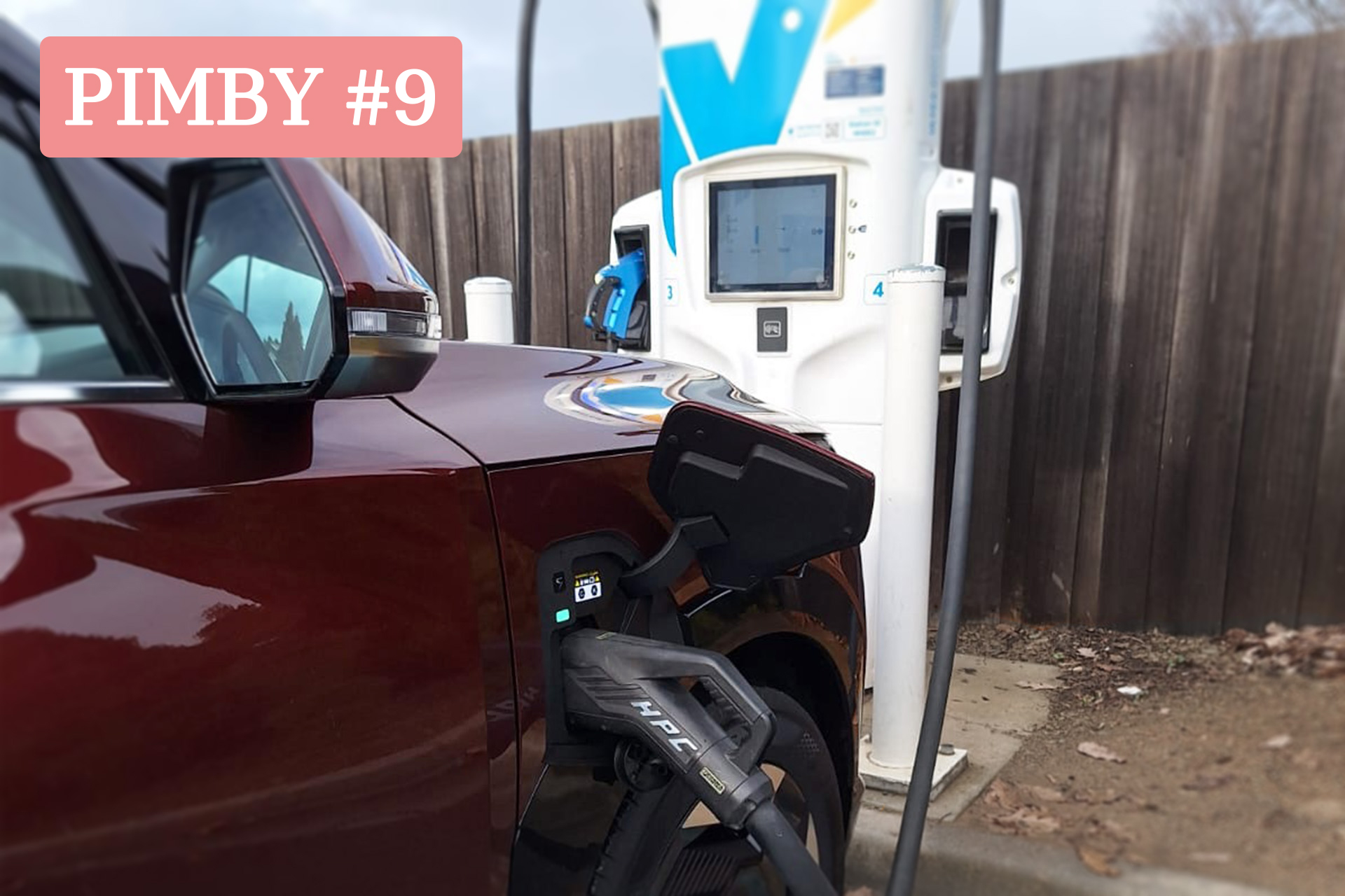This is an image of a dark red electric vehicle charging through a white NRMA charger.