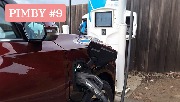 This is an image of a dark red electric vehicle charging through a white NRMA charger.
