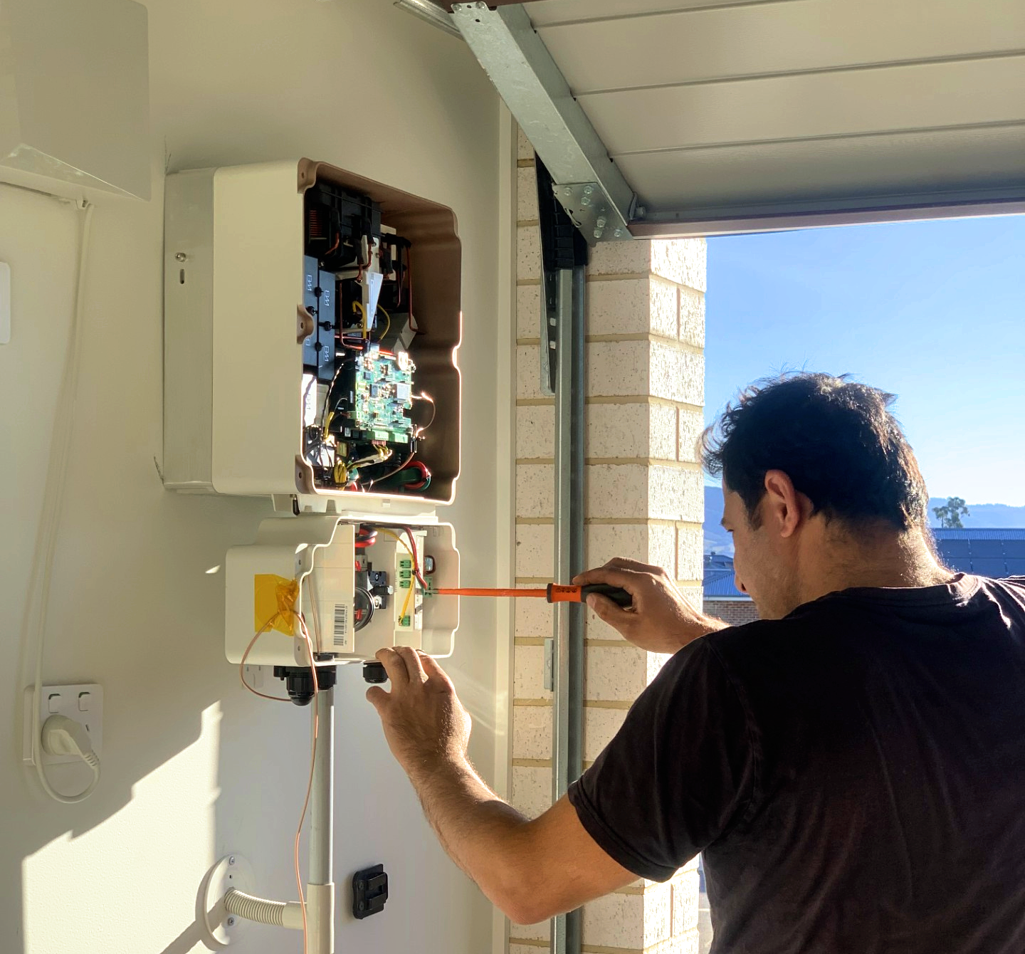 Decarby technician working on wall-mounted solar battery equipment