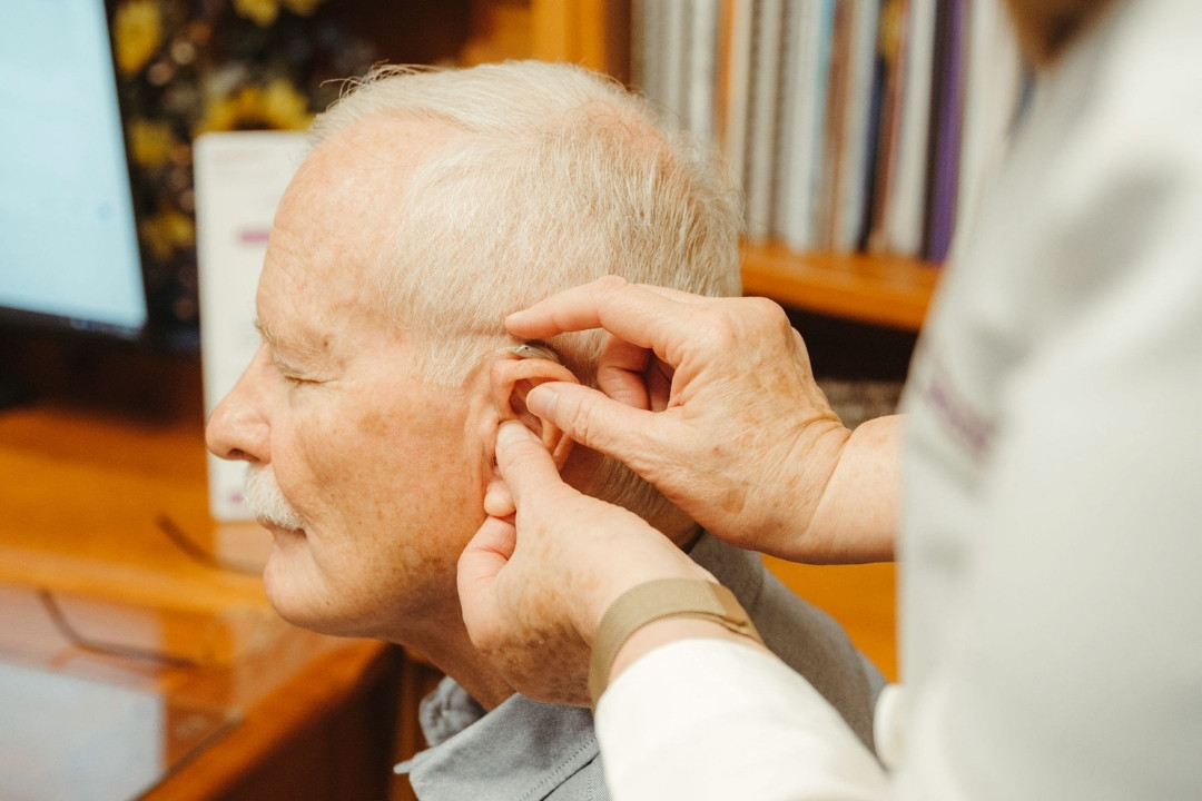 Hearing care professional cleaning and servicing a hearing aid