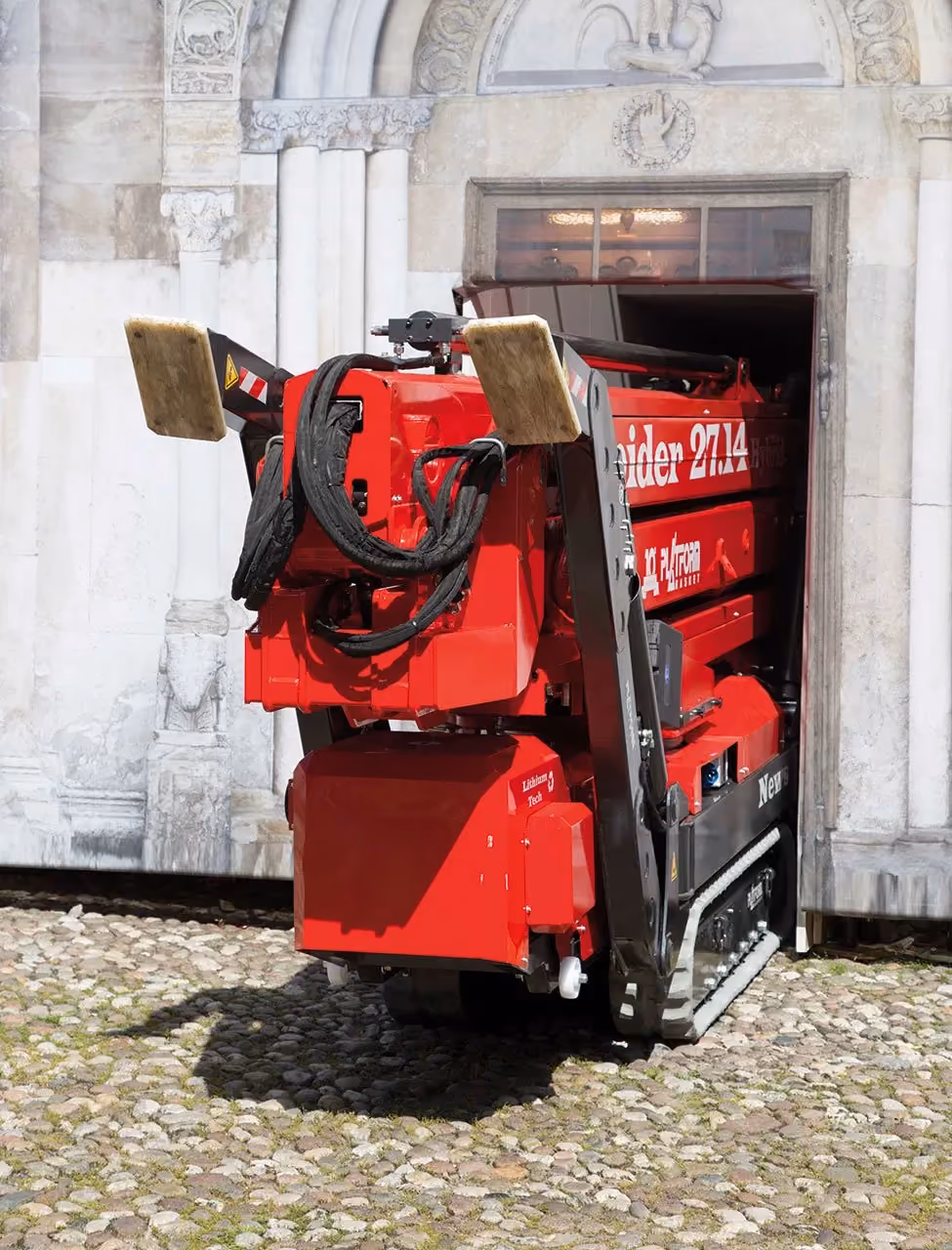 Red Spider 27.14 tracked aerial platform vehicle in a stone courtyard near an ornate archway.