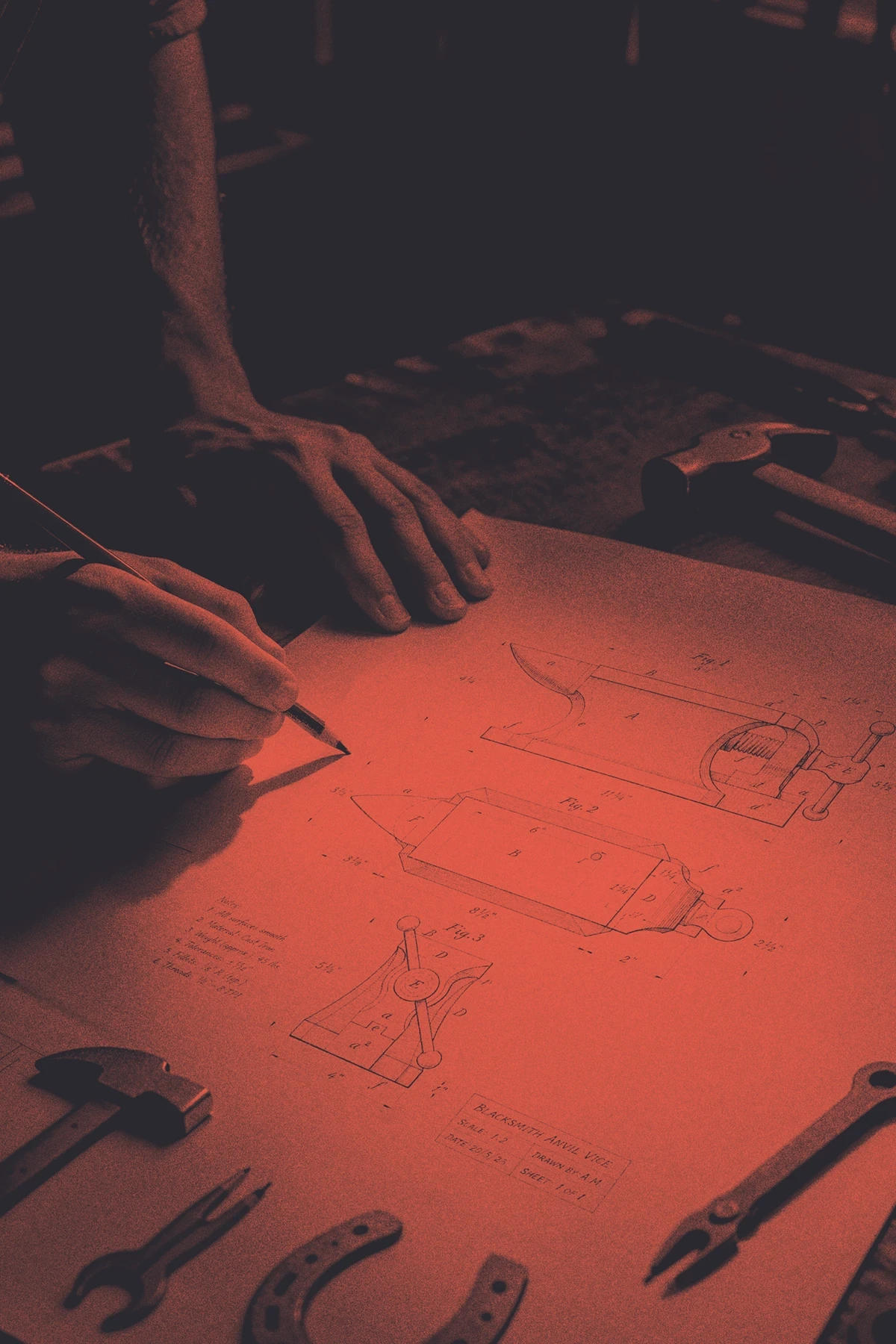 Hands drawing on an anvil vice blueprint in a dark workshop, with technical sketches highlighted in red light.