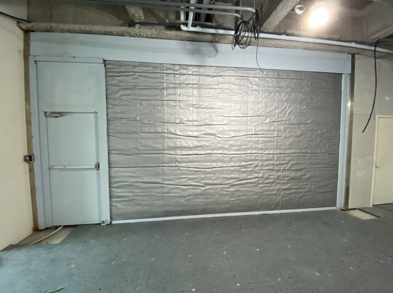 一個帶有灰色隔熱材料的大型車庫門和一個旁邊有標籤的白色門。