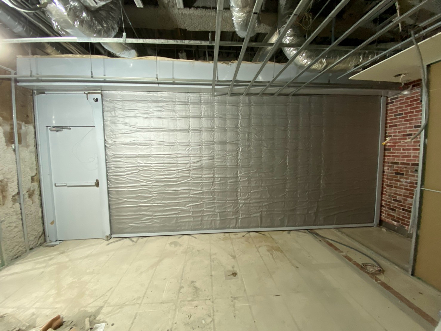 室內施工現場有隔熱門和裸露的管線，地板和牆壁未完成。