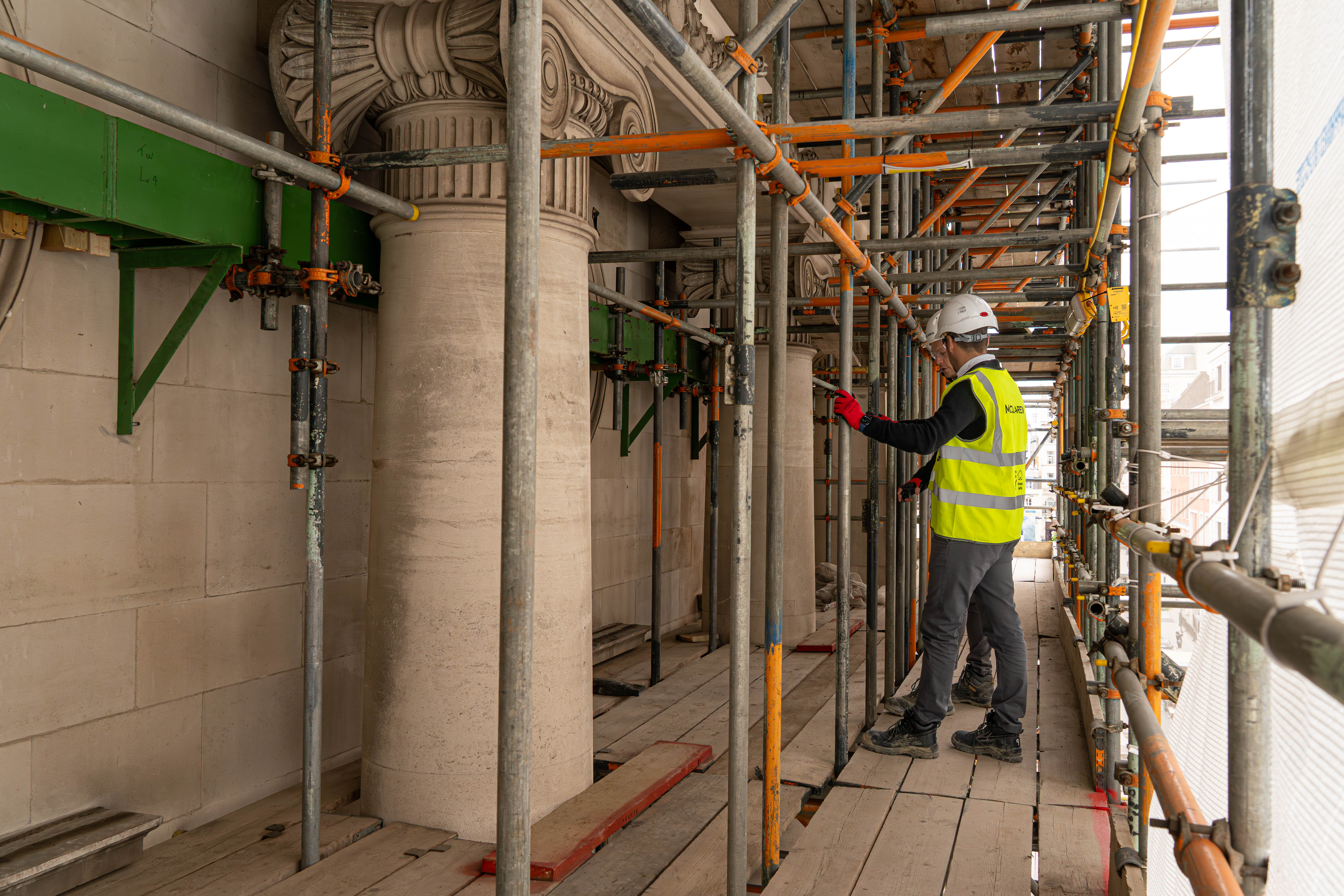 A man in a yellow vest and safety vest working on a building.
