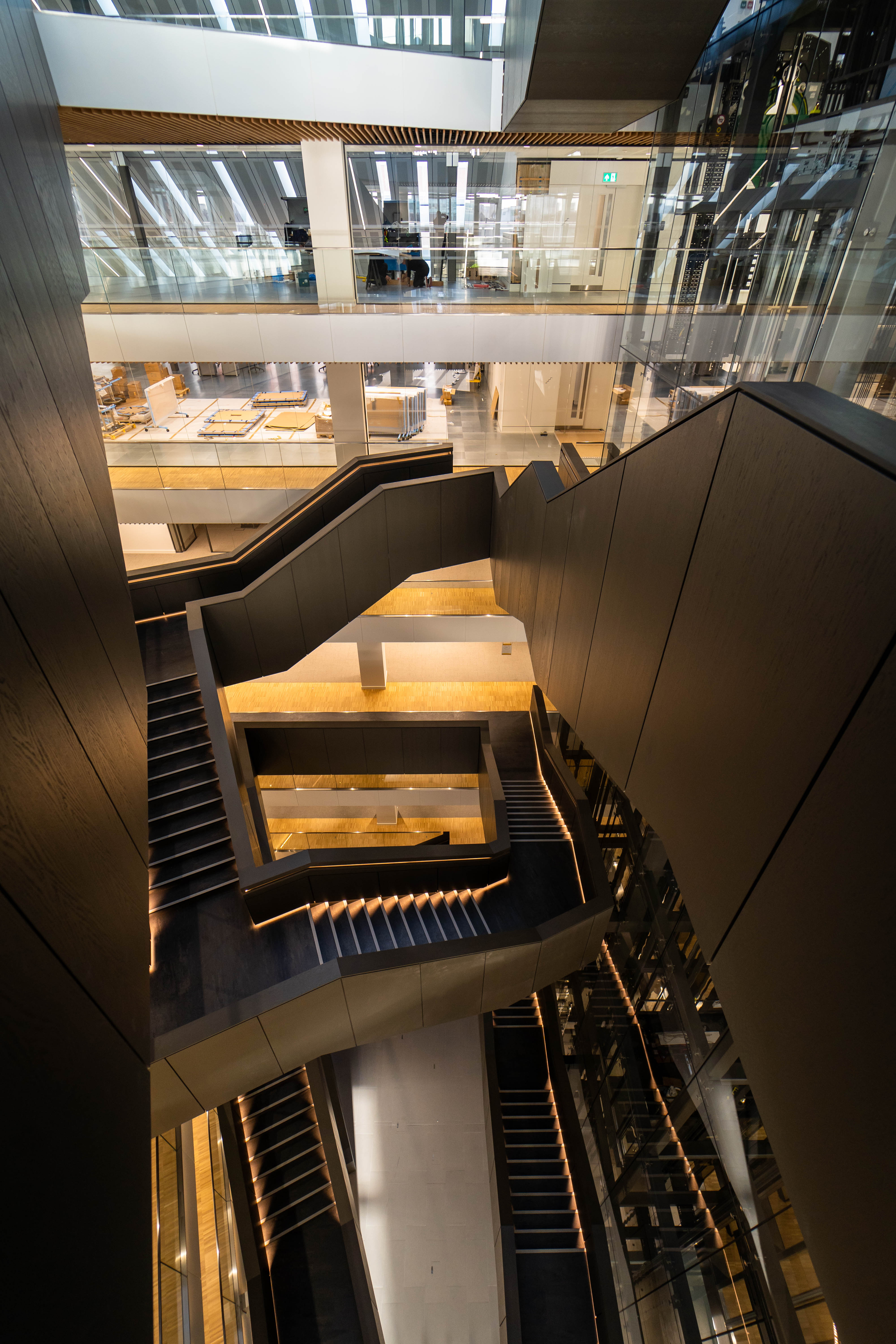 An escalator in a large building with a lot of windows.