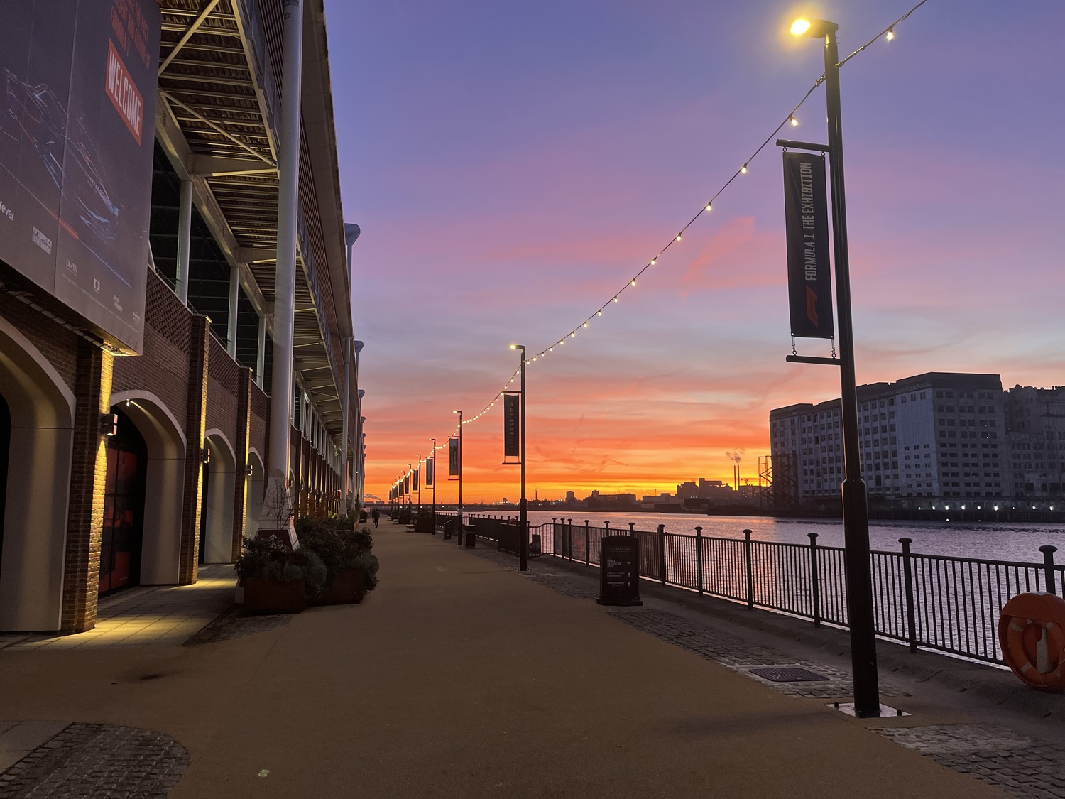 A walkway next to a body of water at sunset.