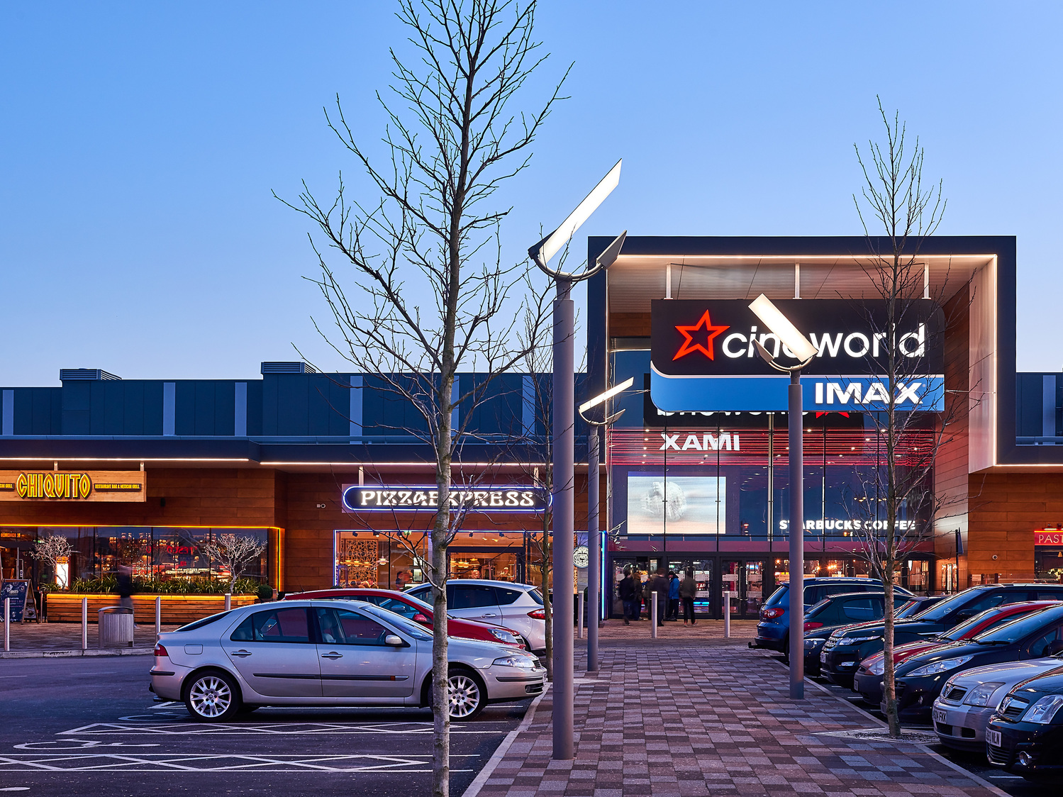 A shopping center with cars parked in front of it.