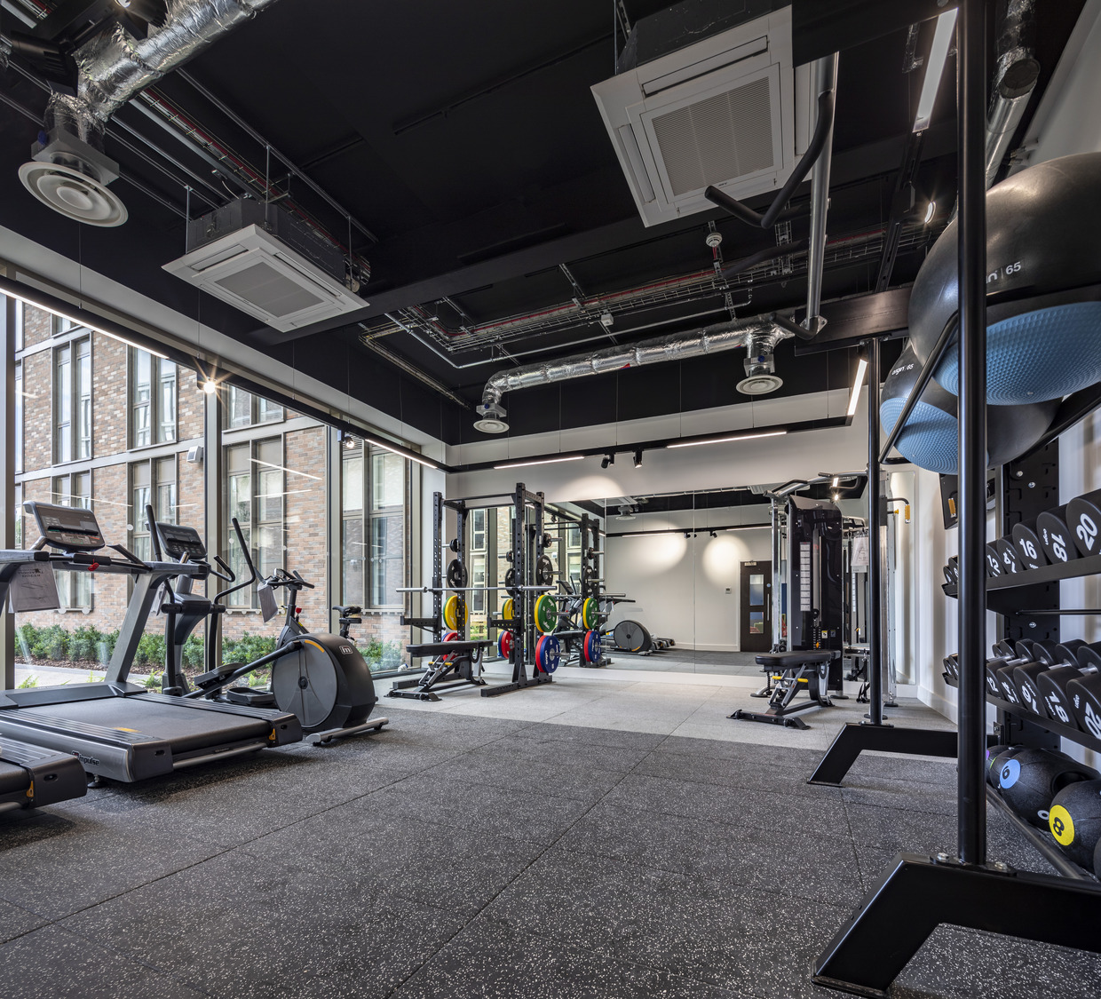 A gym with a lot of machines and a lot of windows.