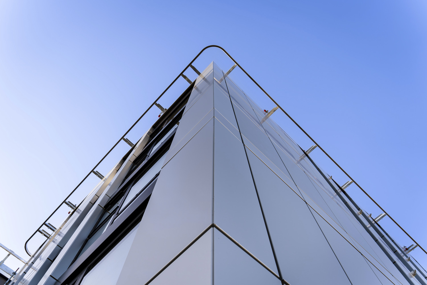 A tall glass building with a sky background.