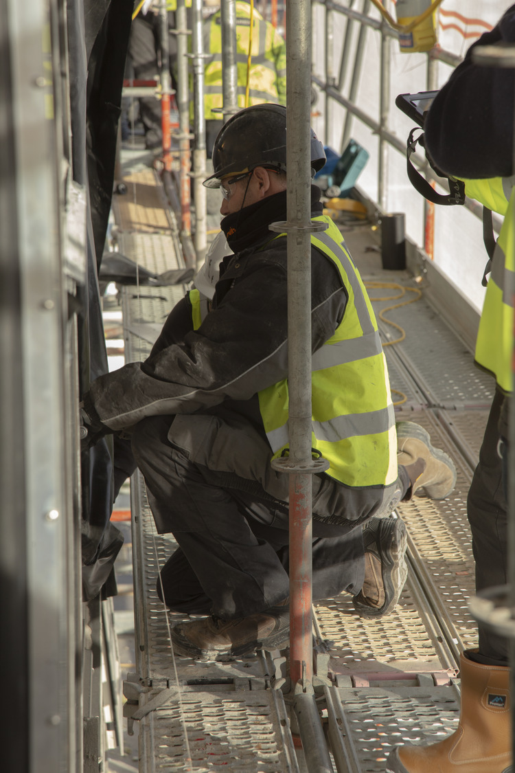 A man in a safety vest working on a metal structure.