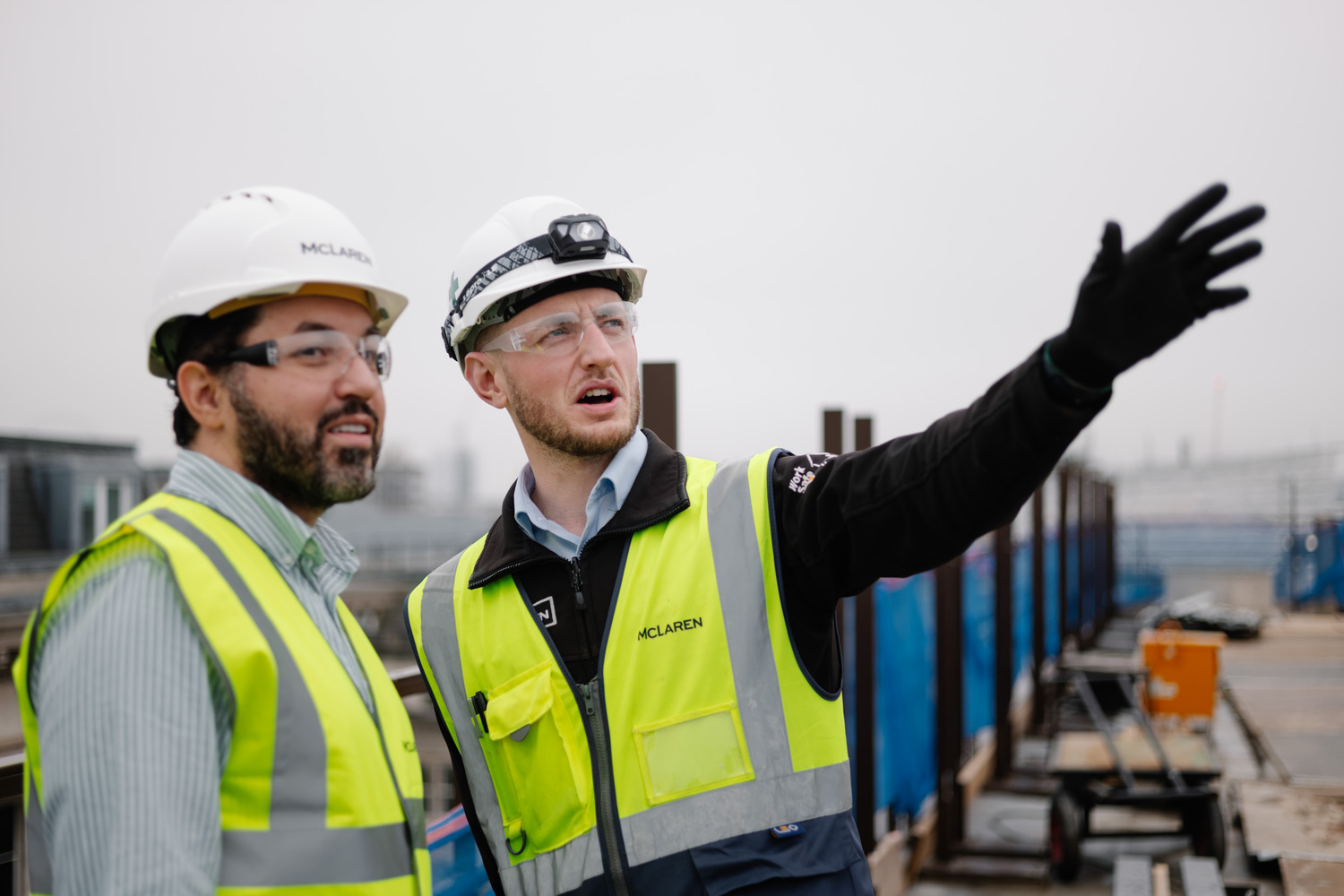 Two men in safety vests standing next to each other.