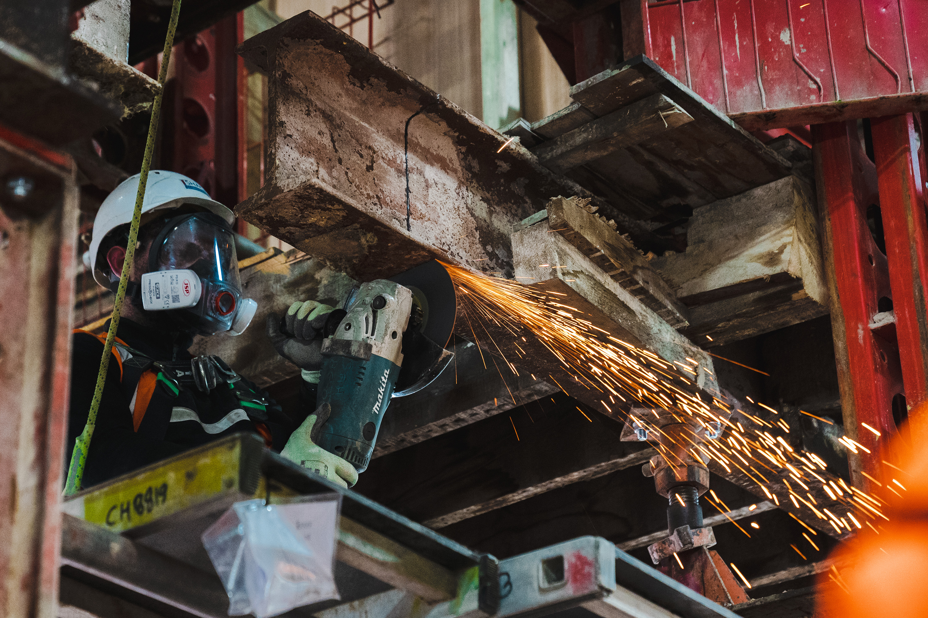 A man in a hard hat grinding metal with a grinder.