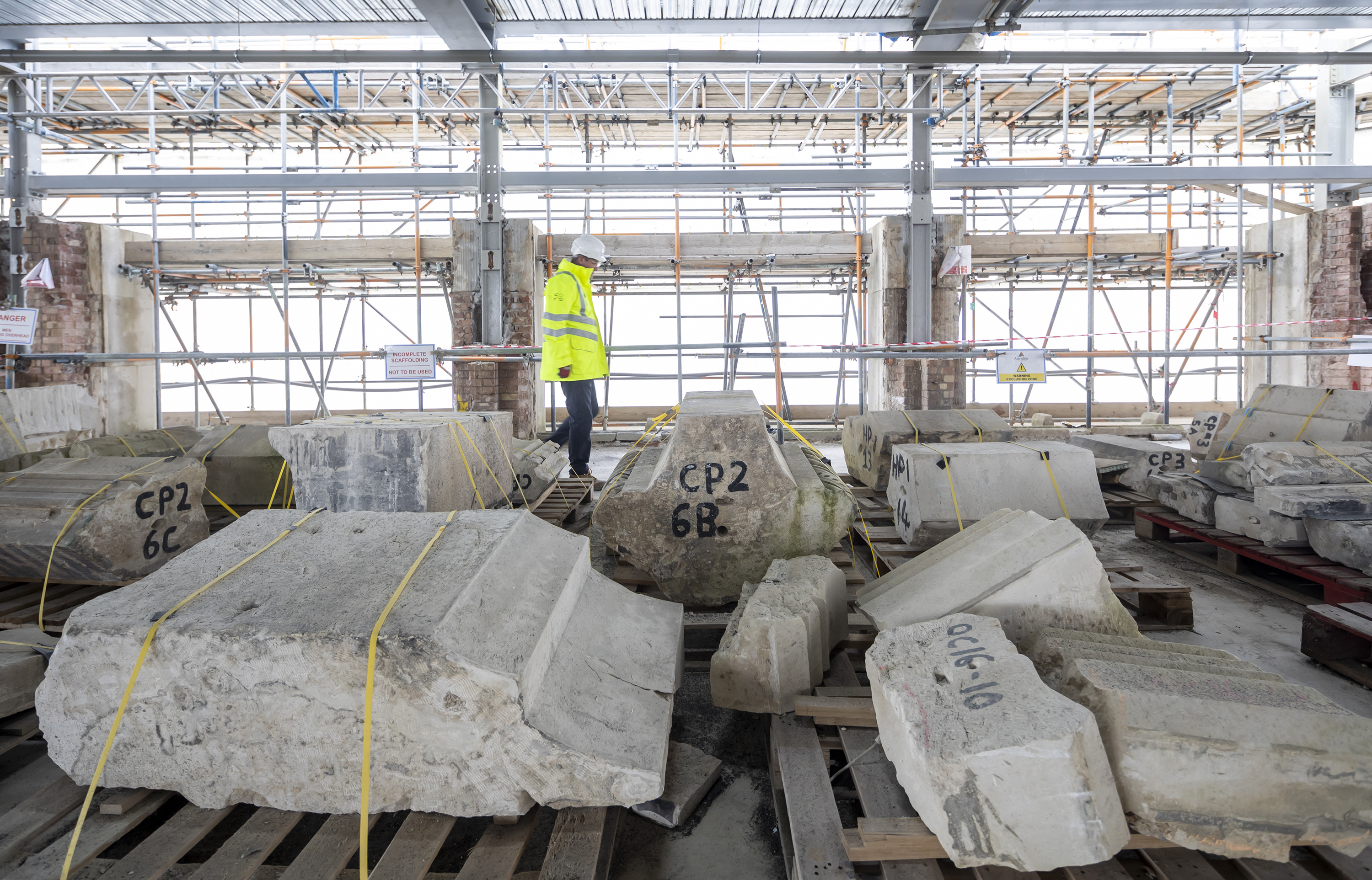 A man in a yellow vest standing next to some large rocks.