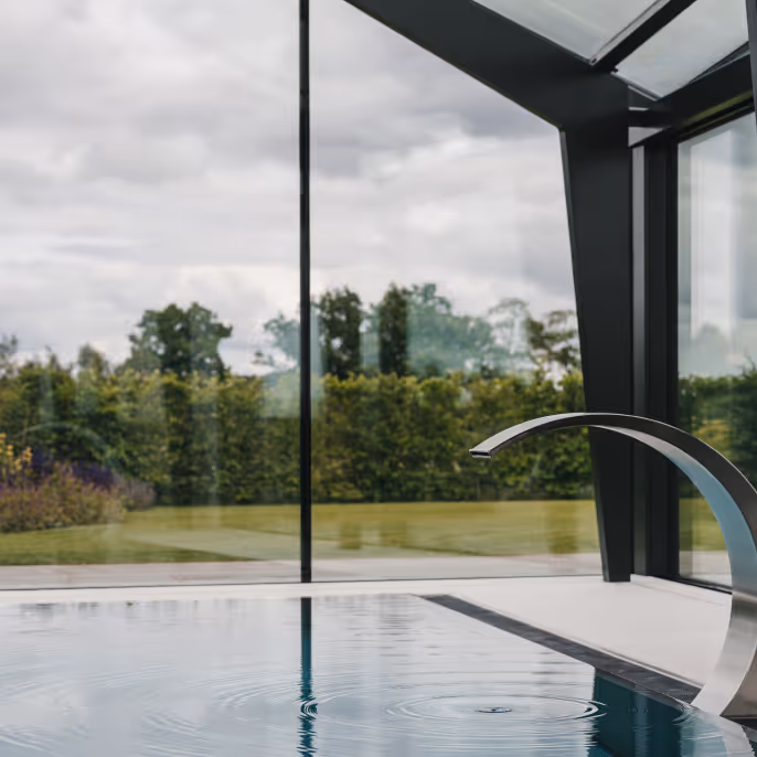 A room with large windows and outdoor greenery