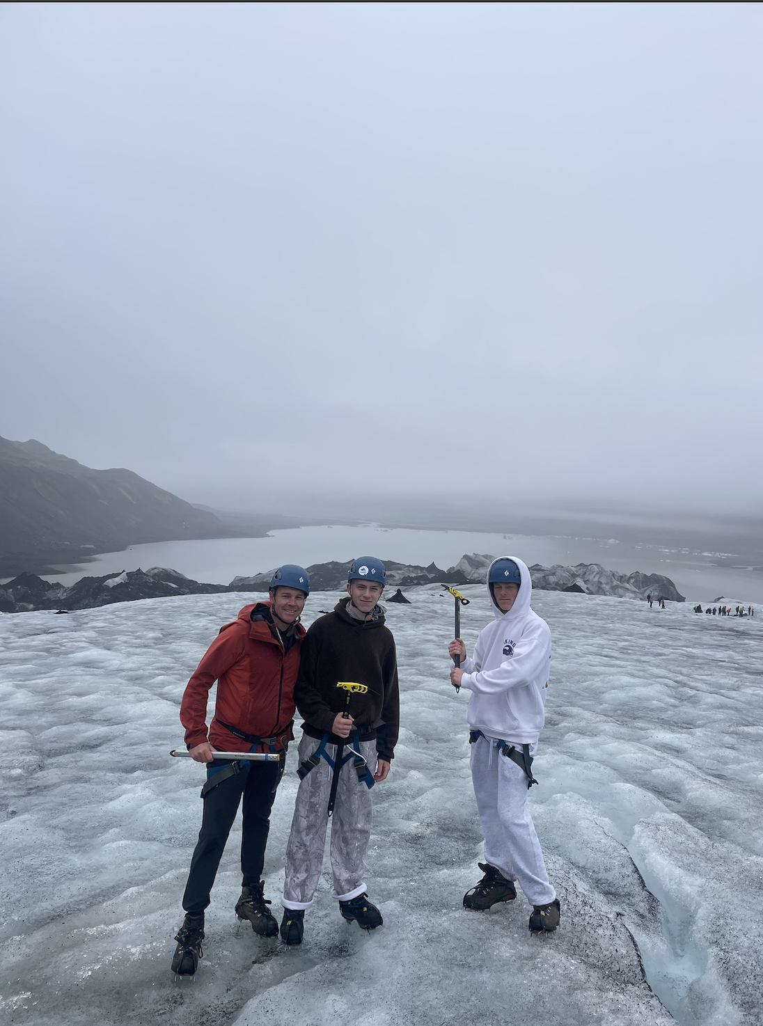 Travelers hiking on Sólheimajökull Glacier in Iceland wearing crampons and safety helmets.