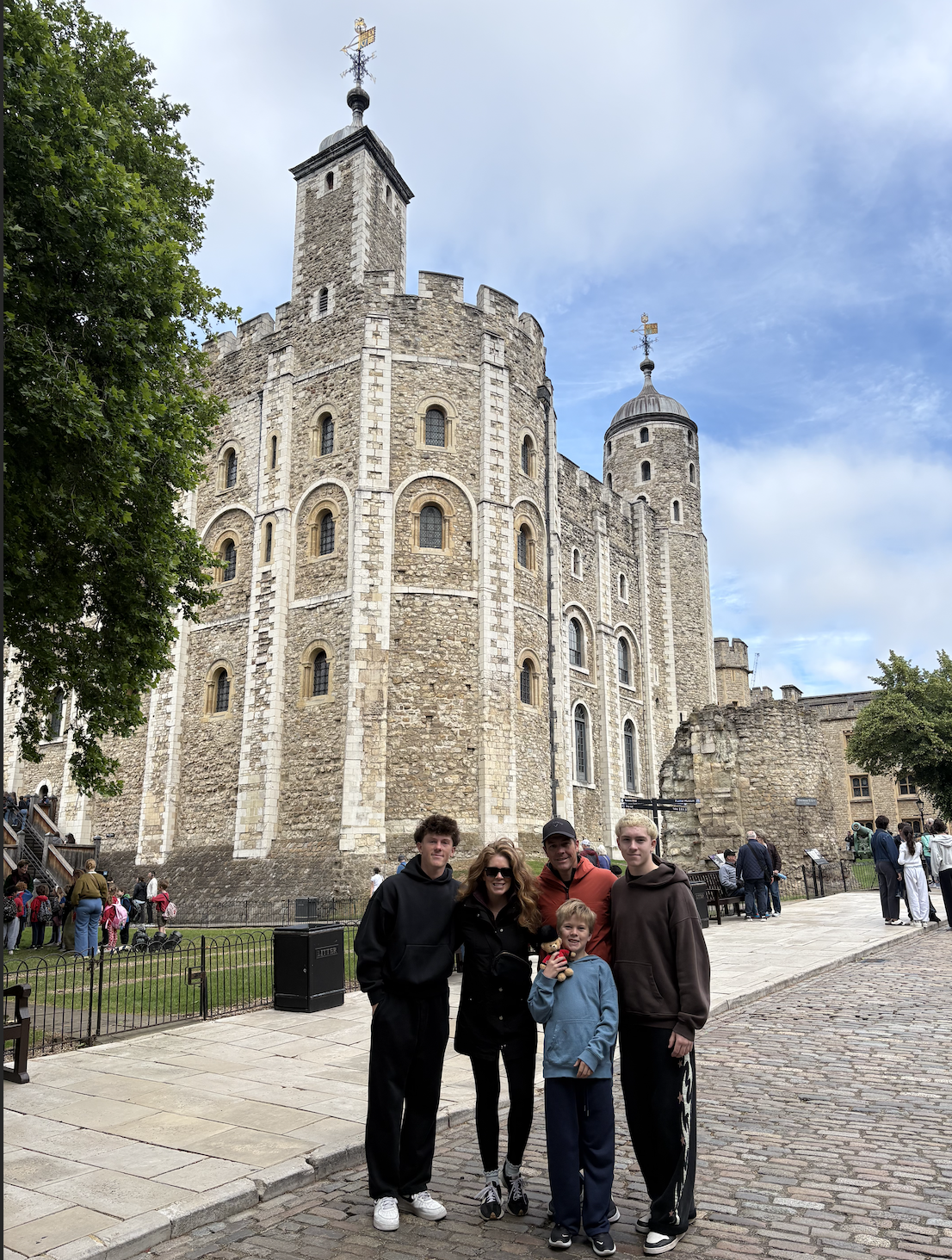 Family posing in front of the historic White Tower at the Tower of London, England.