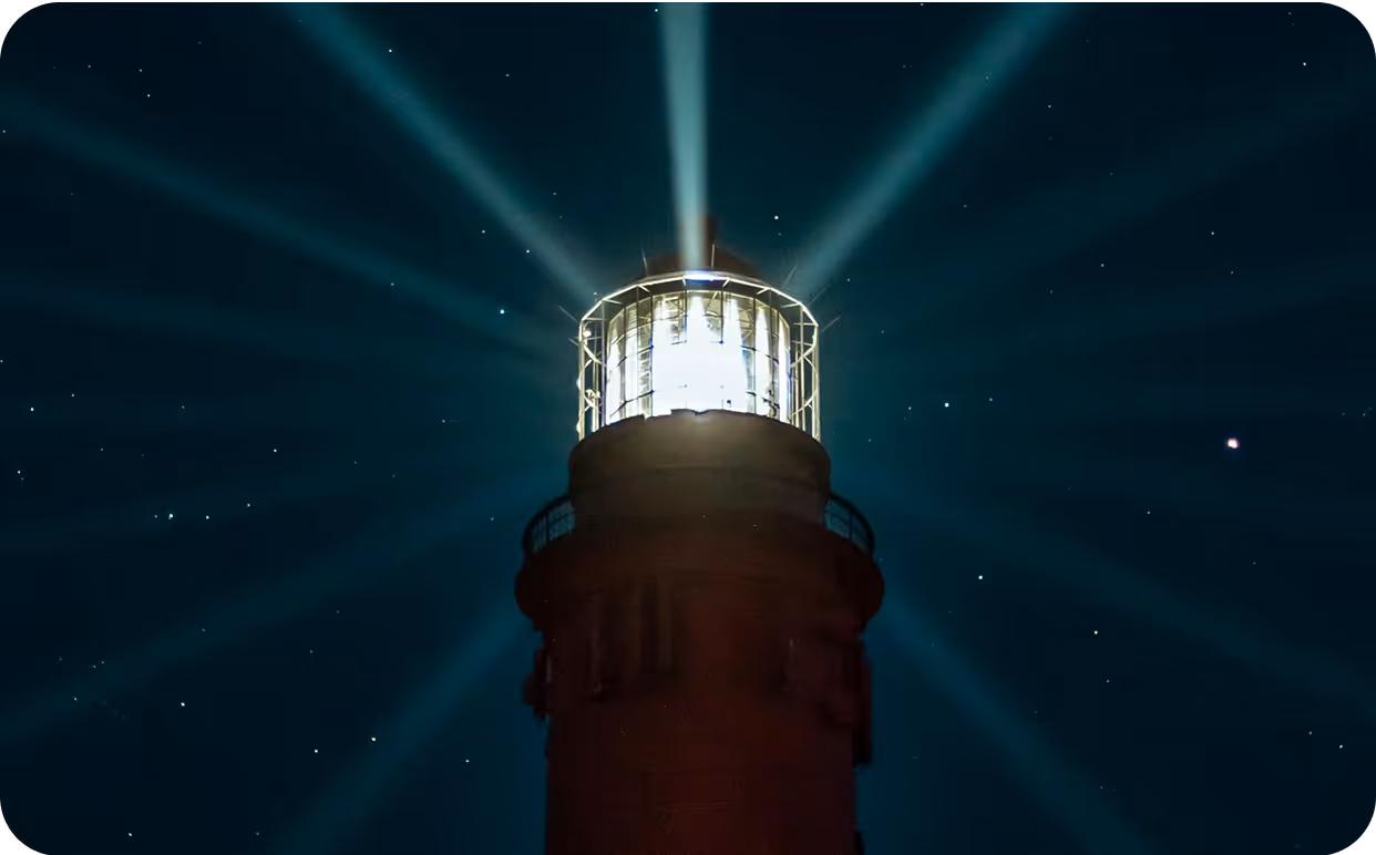 A lighthouse with a light shining on top of it.