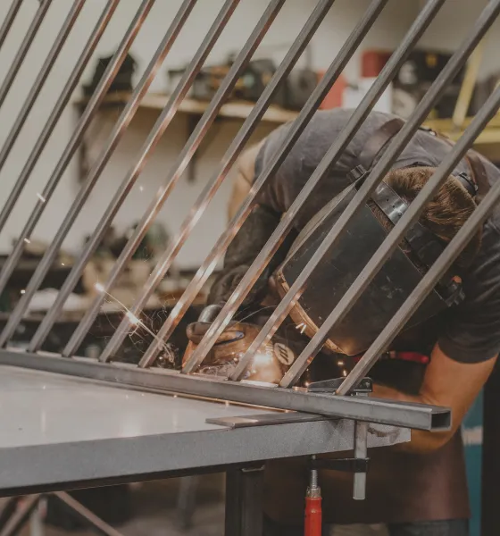Welder leaning into work on angled metal project