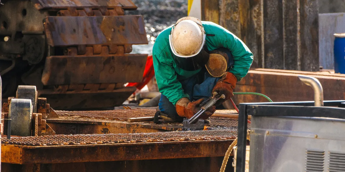 Welder outside kneeling while working