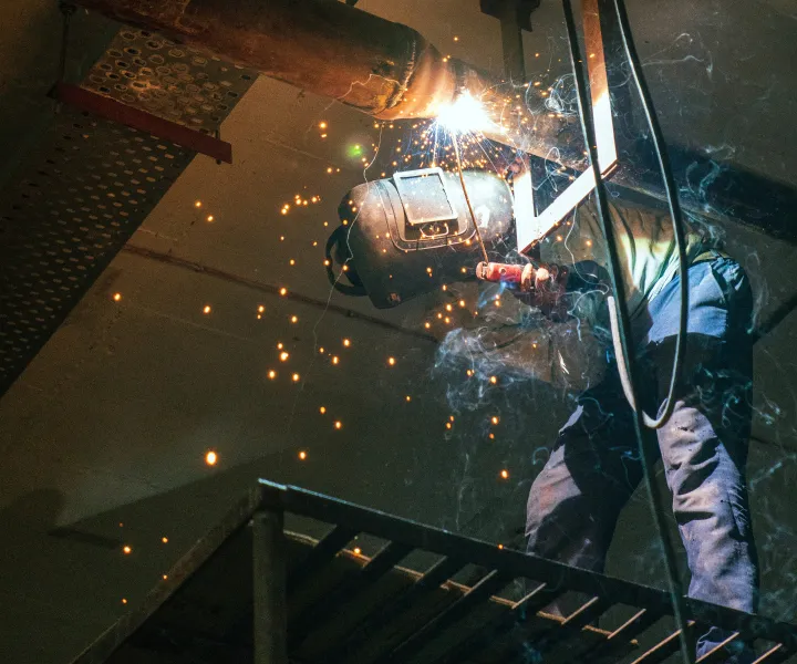 Welder looking up at weld while standing on platform