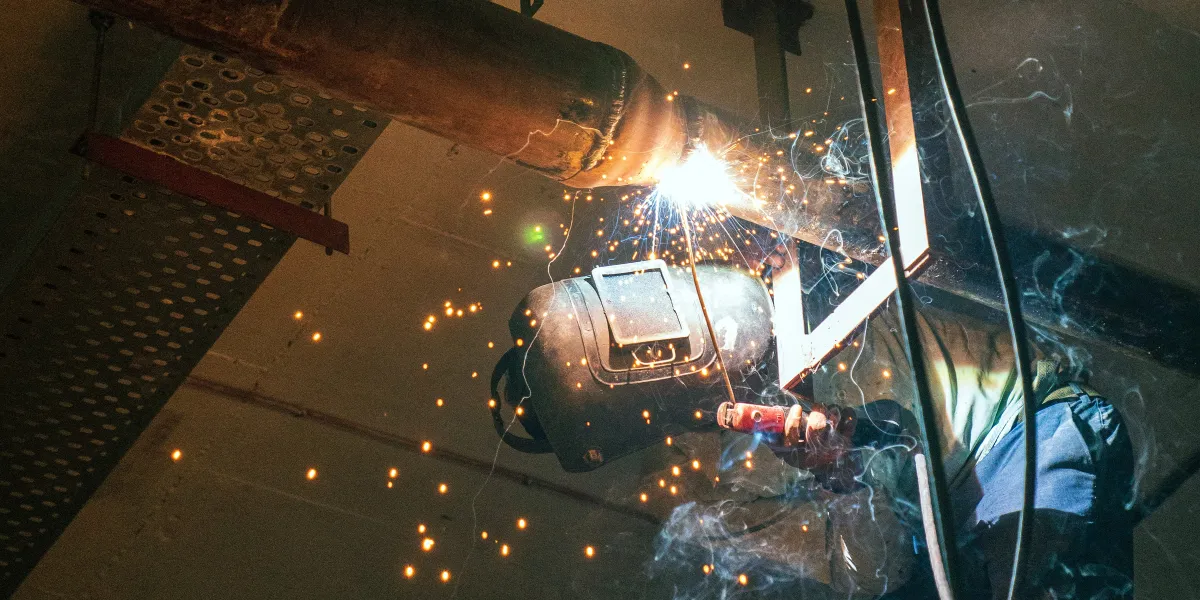 Welder looking up at weld while standing on platform