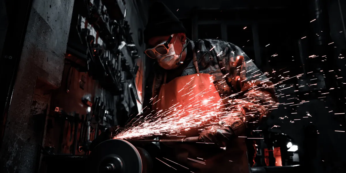 Welder in dark room grinding with red sparks