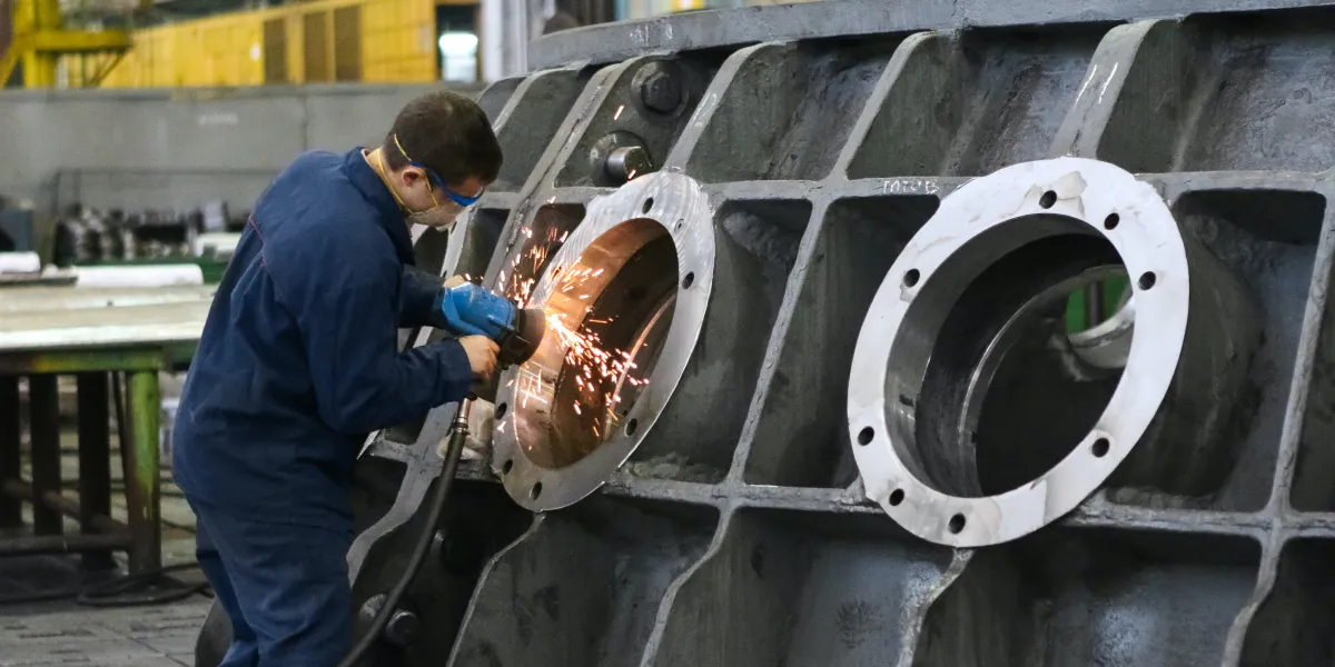 Worker smoothing metal with grinder
