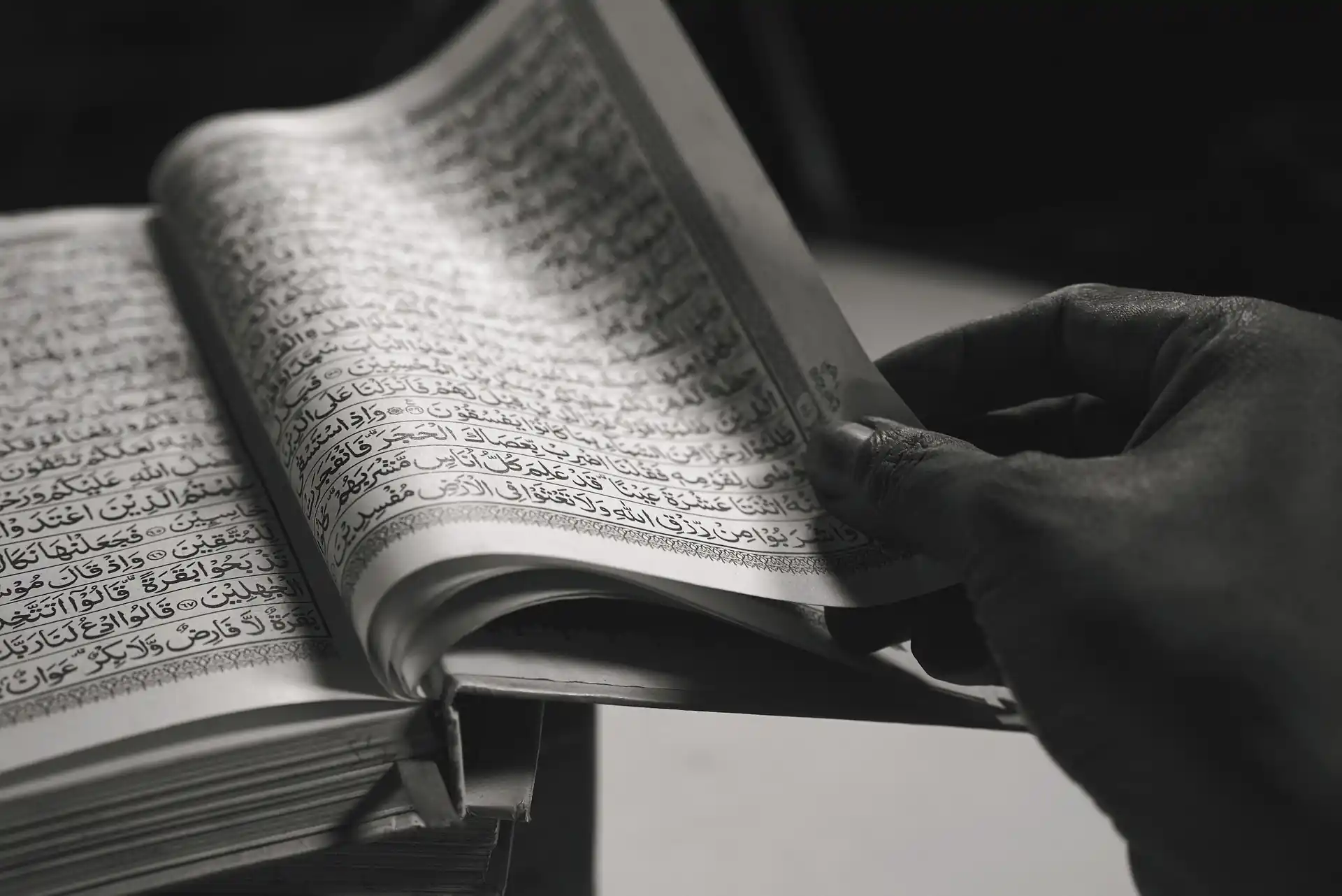 Sabr in Islam Blog Image: Hand turning a page of the Quran