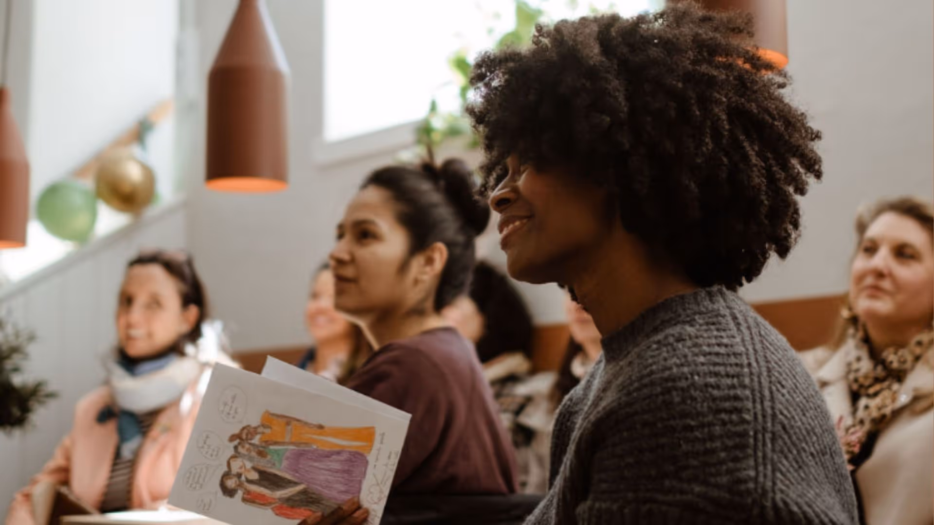Group of people smiling and engaging in Mon Village Caîo café in Stockholm during workshop