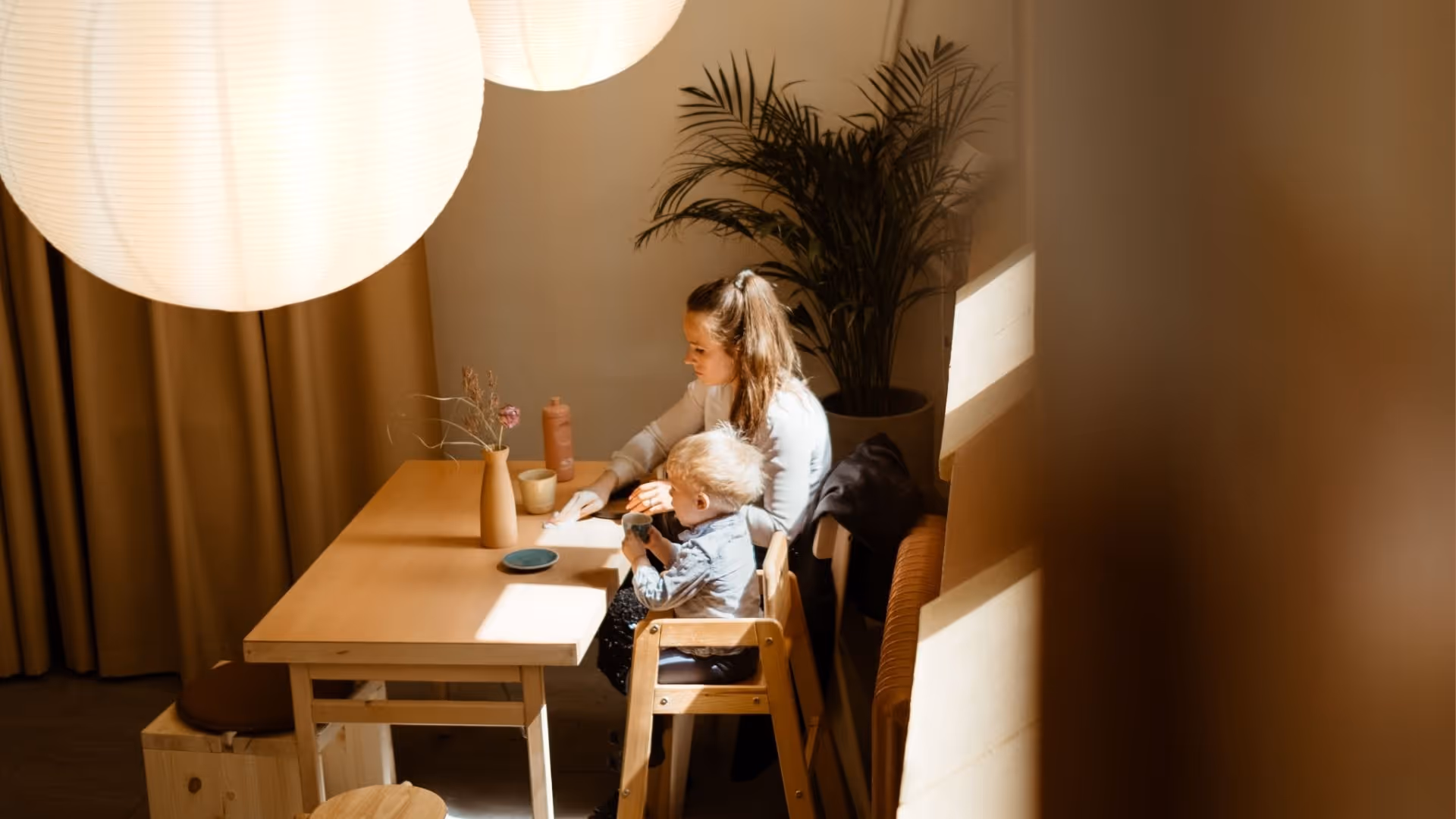 Mother and child enjoying a cozy moment at Mon village caîo café in stockholm with warm wooden furniture and natural light