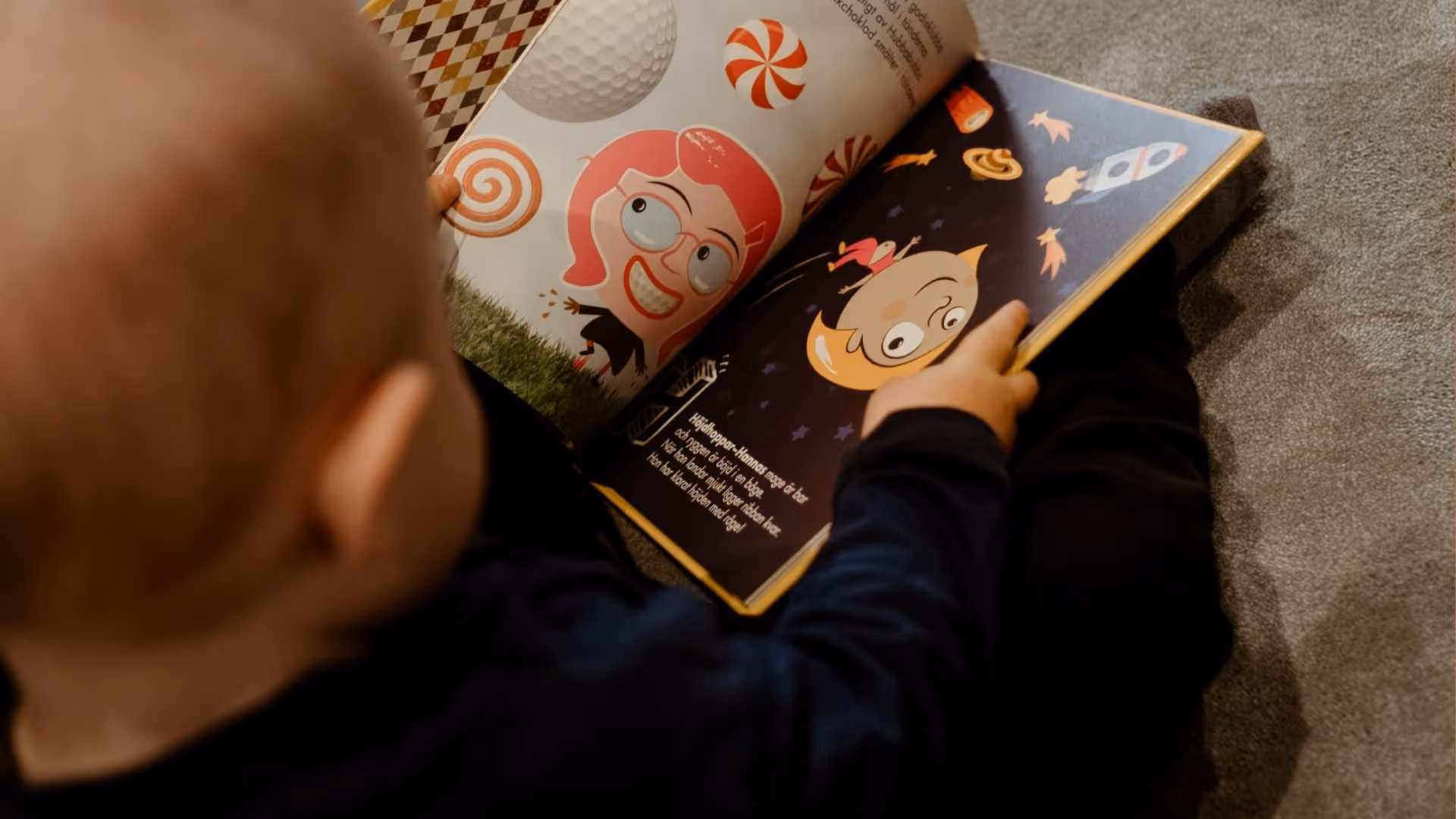 Child reading a colorful illustrated book featuring cartoon characters and playful designs.