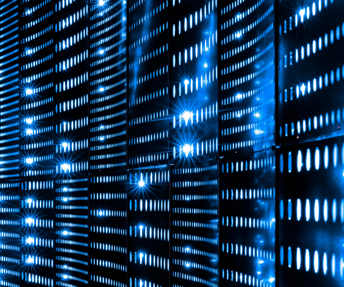 Rows of illuminated blue server racks with glowing horizontal vents in a data center.