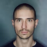 A man with a bald head is looking at the camera.
