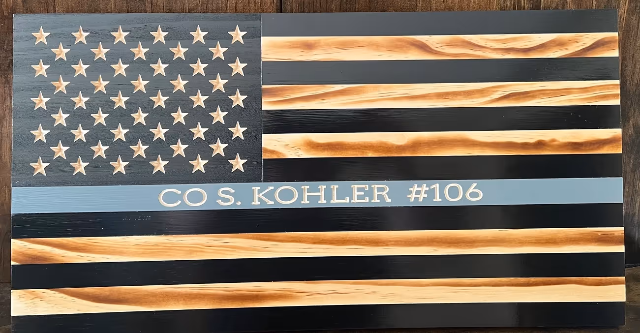 Wooden American flag with black and natural wood stripes and text CO S. KOHLER #106 on a blue stripe.