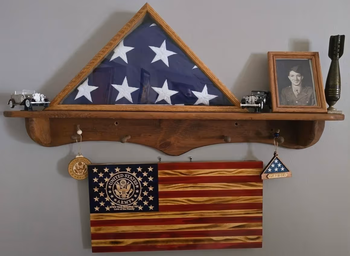 Wood shelf with folded American flag, vintage toy cars, framed soldier photo, and patriotic decorations.