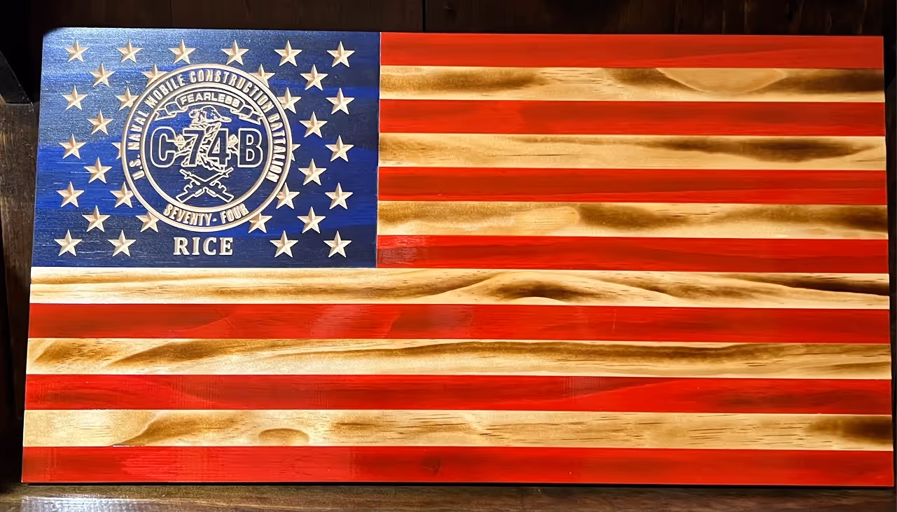 Wooden American flag with U.S. Naval Mobile Construction Battalion 74B emblem and name Rice engraved.