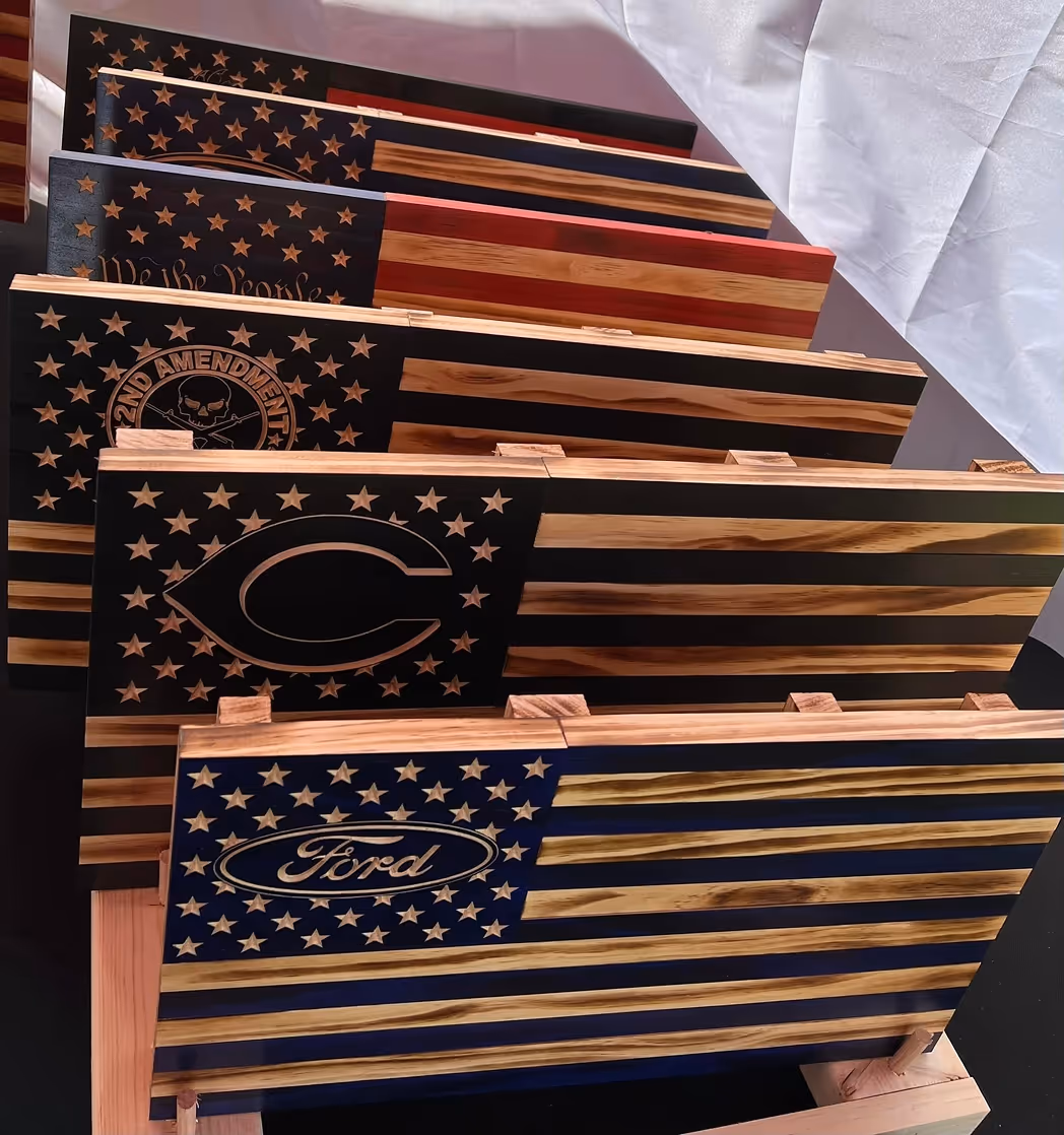Wooden American flags with logos and symbols engraved in the star field, displayed on stands.