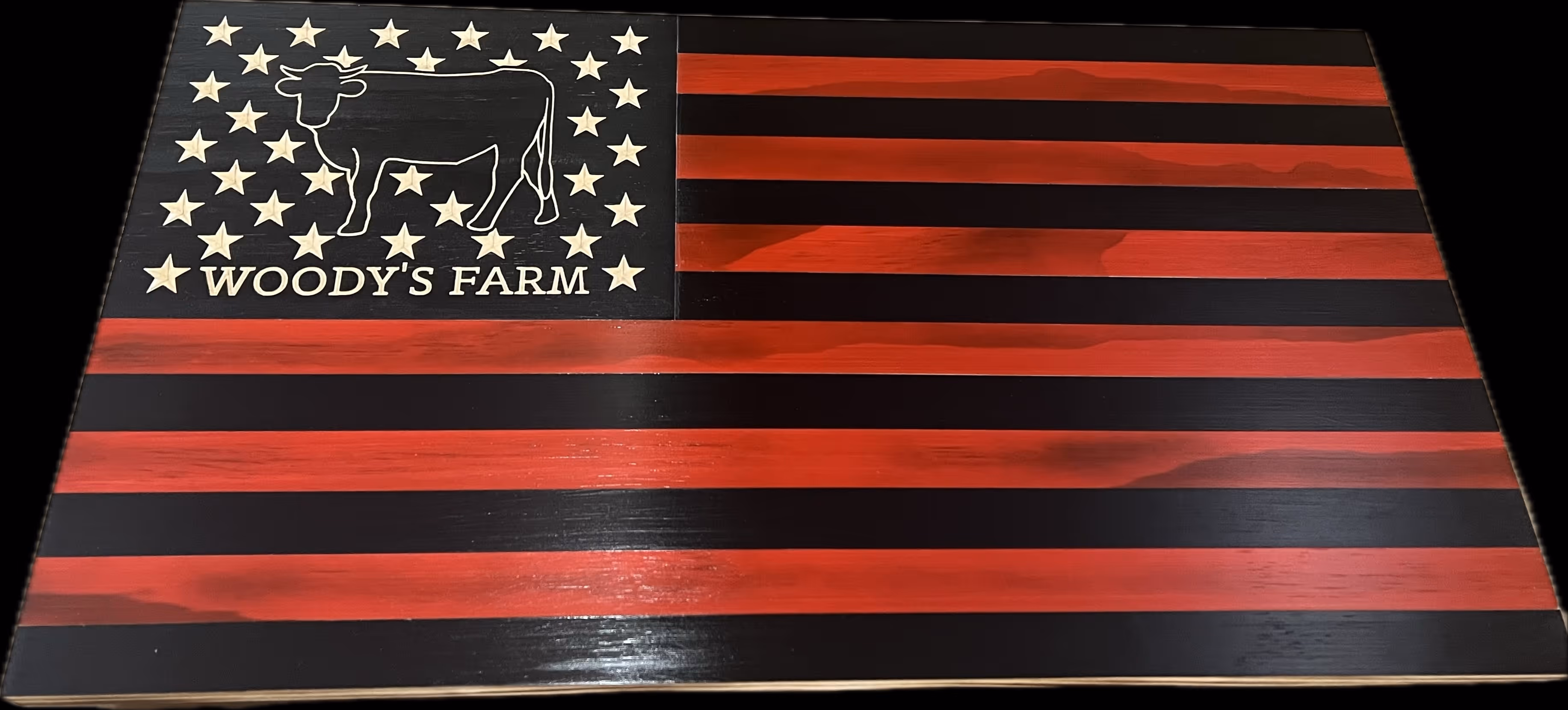 Wooden flag painted red and black with stars, a cow, and the text Woody's Farm.