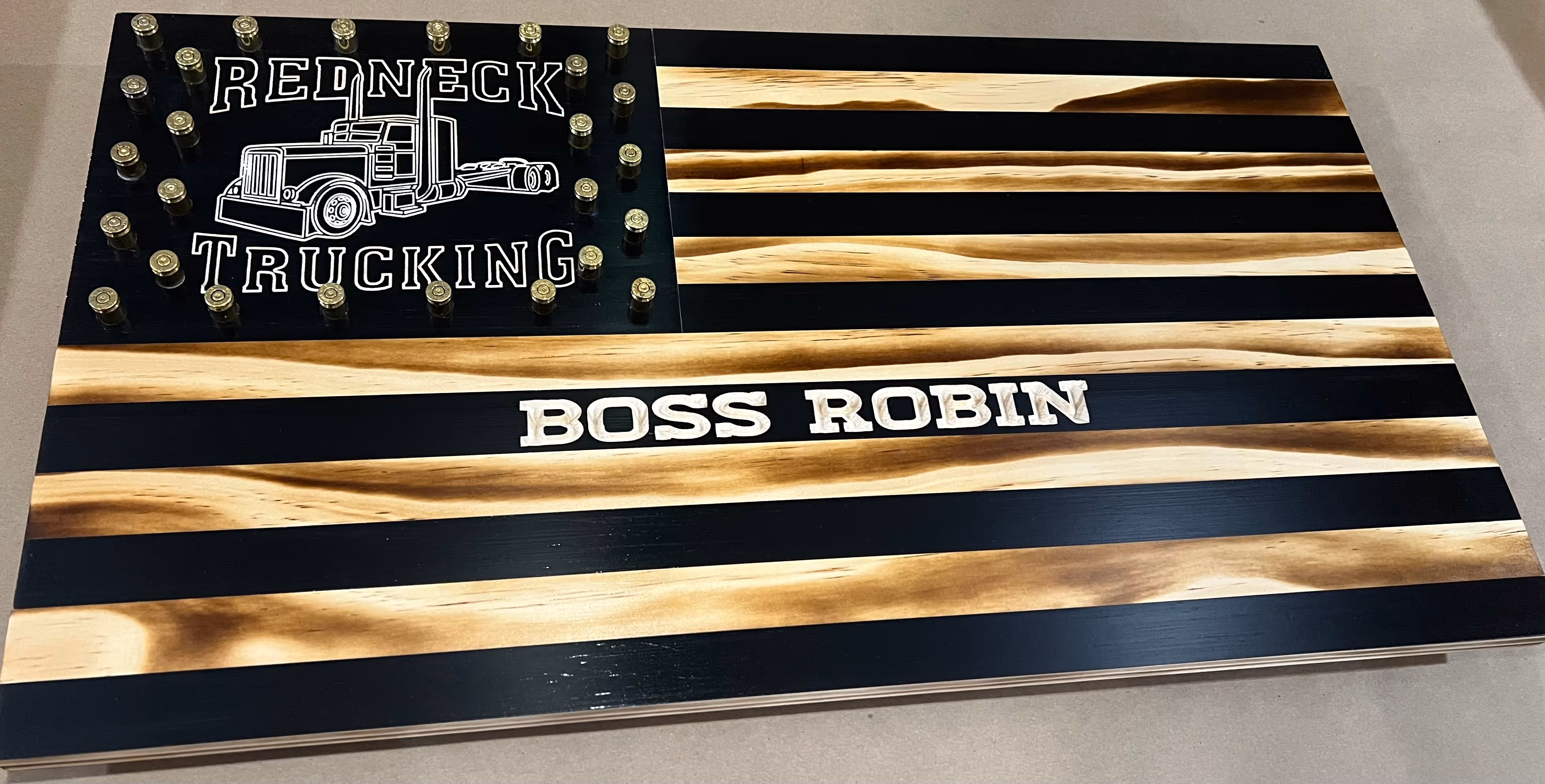 Wooden American flag with ‘REDNECK TRUCKING’ and a truck image, and ‘BOSS ROBIN’ in the stripes.