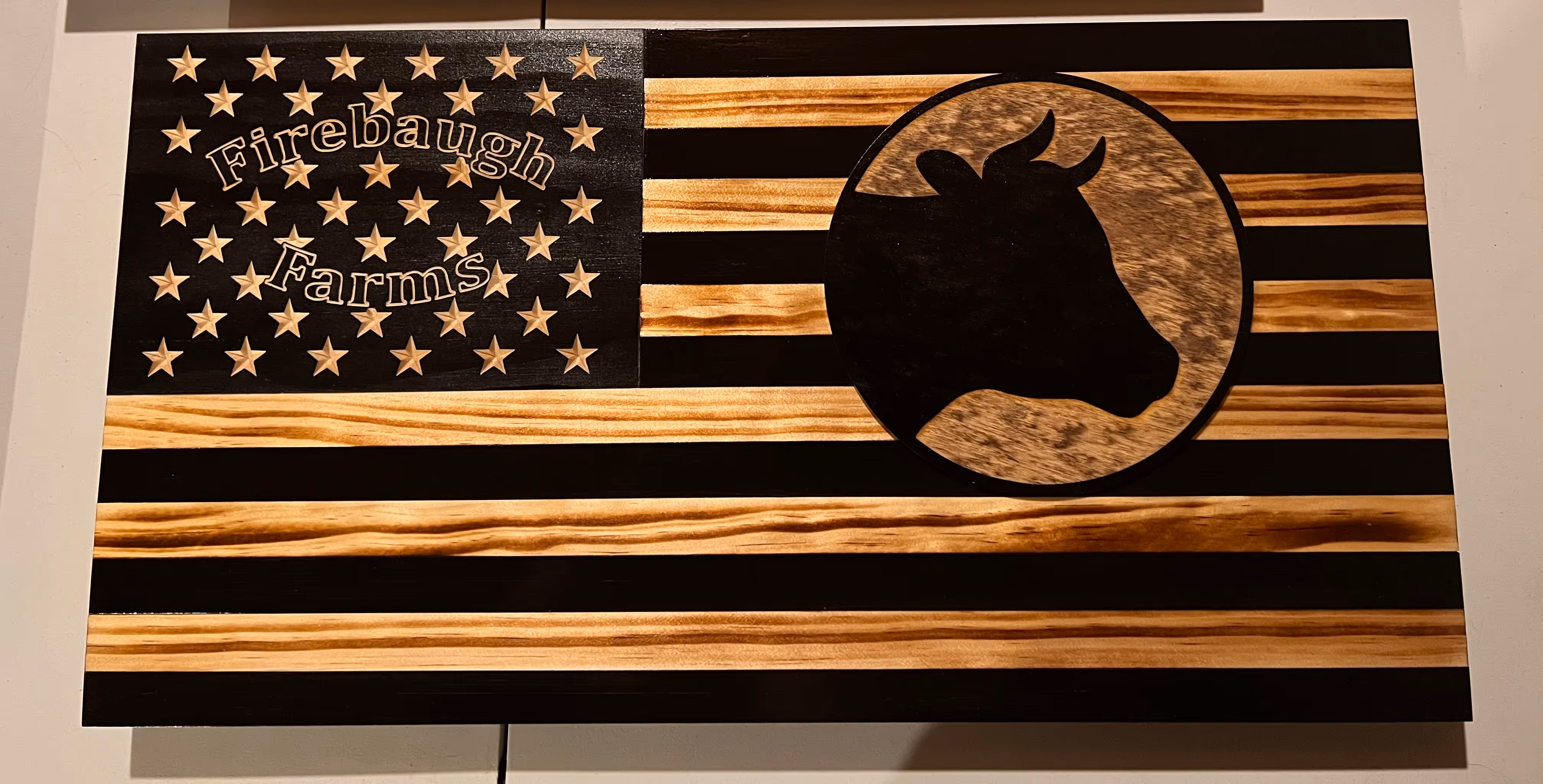 Wooden US flag with Firebaugh Farms text and cow silhouette in a circle on the right.